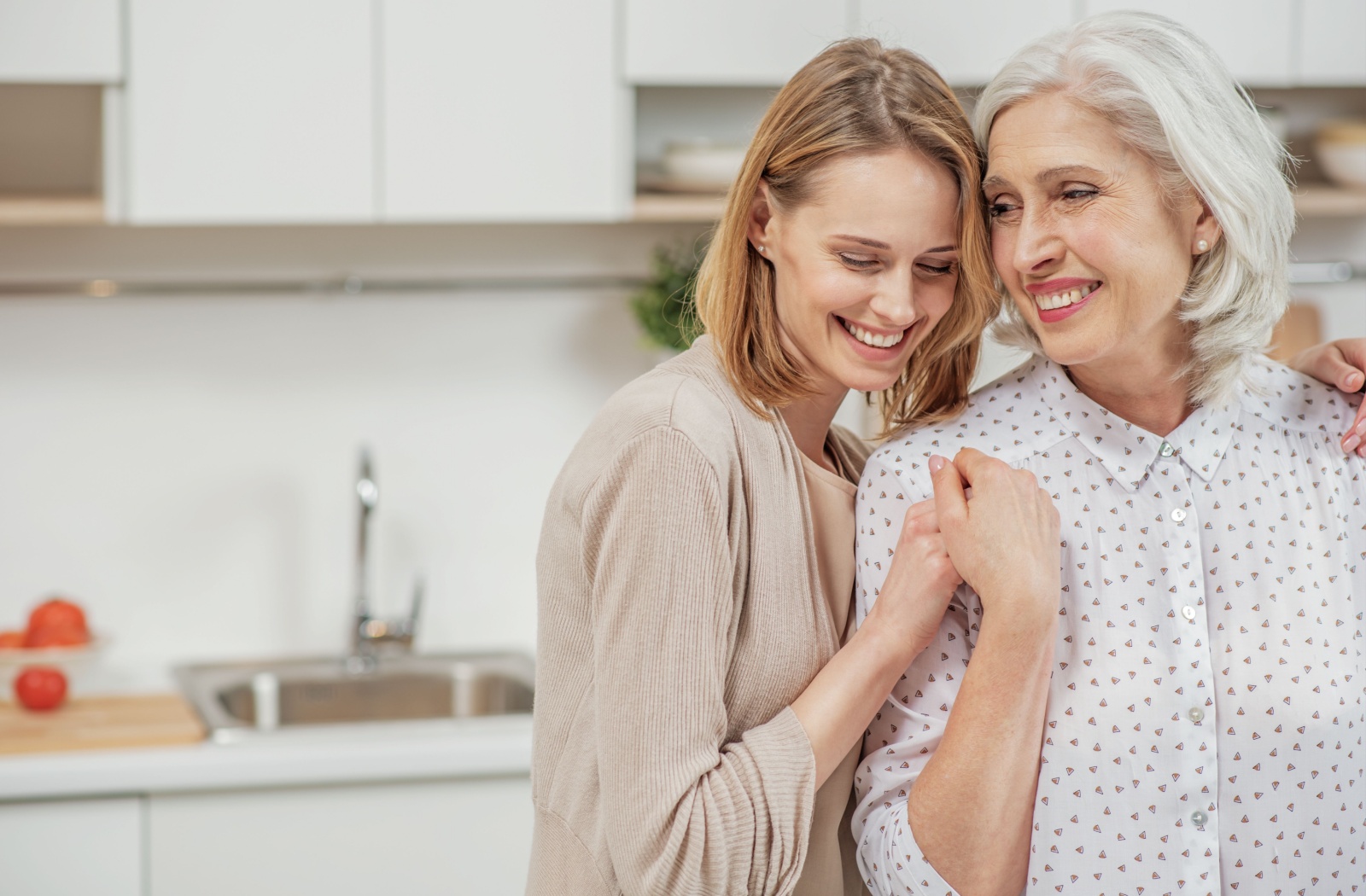 A loving daughter hugging her older adult mother during her visit.