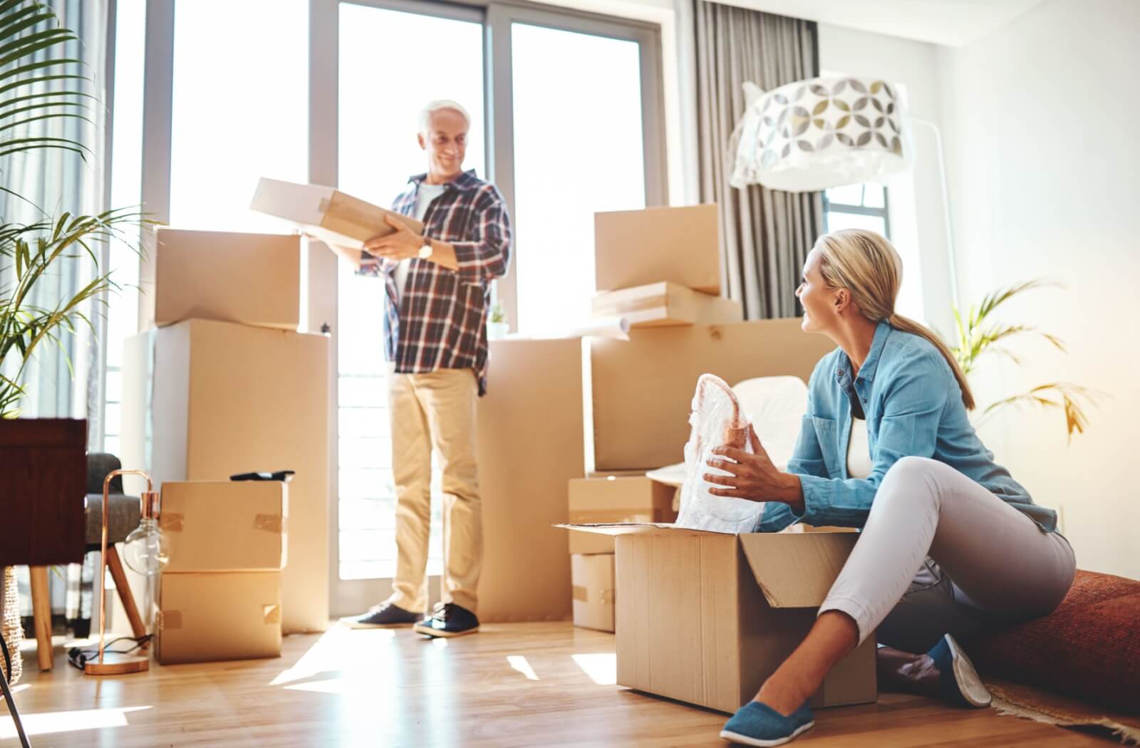 An adult daughter helps her father pack boxes to prepare for his move into a senior living community.