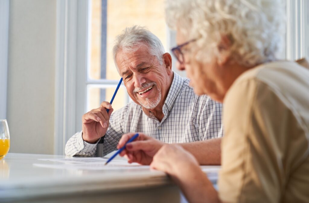 Two happy seniors doing a crossword puzzle.